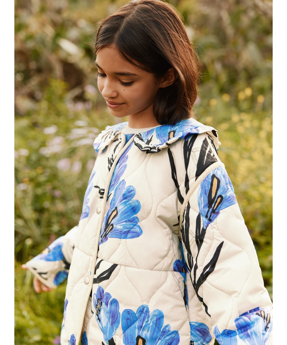 Hailey - Painted Crocus - Off-white wind and water-resistant padded jacket for children made of soft cotton with a wavy quilted pattern and floral print.