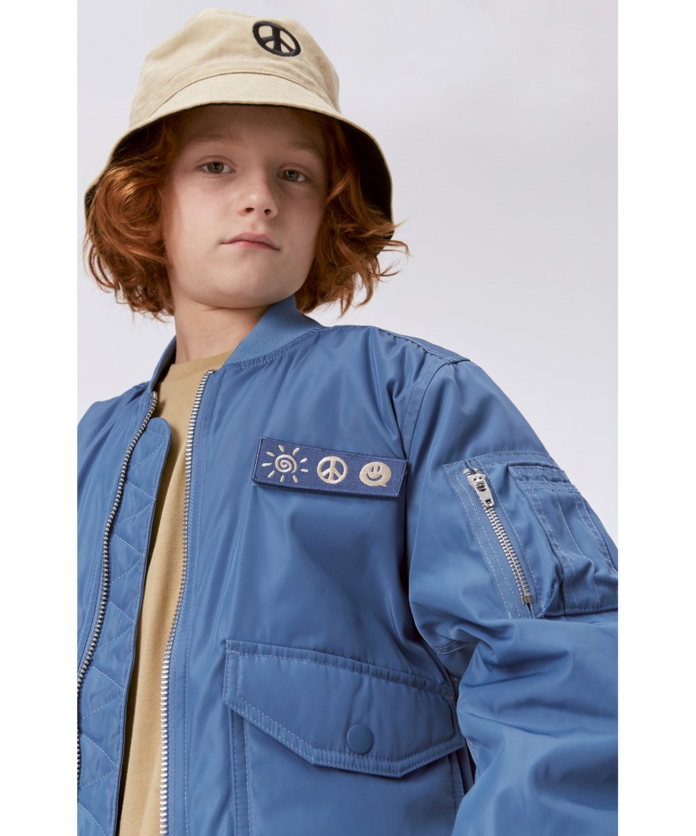 Heath - Moonlight Blue - Blue bomber jacket with sun, peace and smiley face