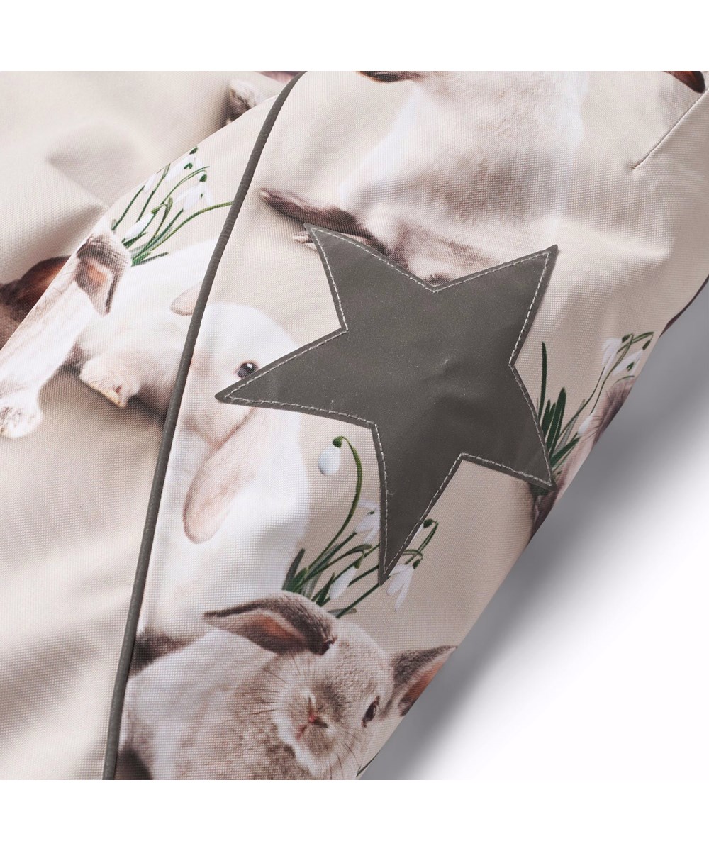 Hopla Fur - Winter Rabbits - Wind- and waterproof winter jacket for children in recycled polyester with a print of cute rabbits among snowdrops on a grey background.