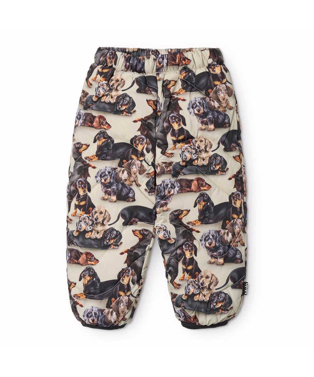 Percy - Dashshund Soft - Water-repellent beige thermal trousers for the little ones with a print of dogs in black and brown shades. It is made of recycled polyester with brown edges.