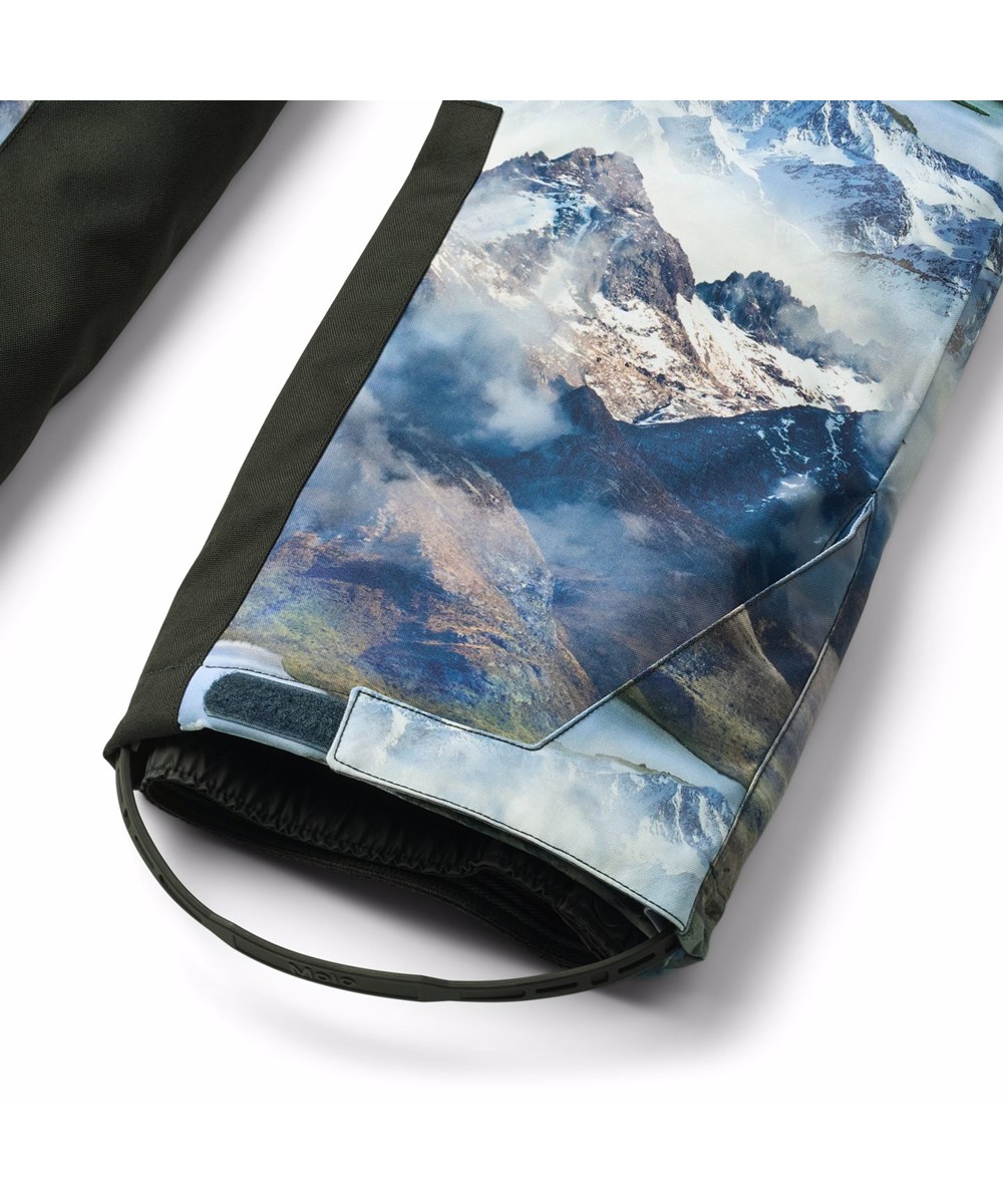 Play Pro - Snowy Mountains - Wind and waterproof ski pants made of recycled polyester with a beautiful landscape print showing snow-capped mountain peaks in vivid colours. The ski pants have adjustable braces and are padded with 3M™ Thinsulate™.