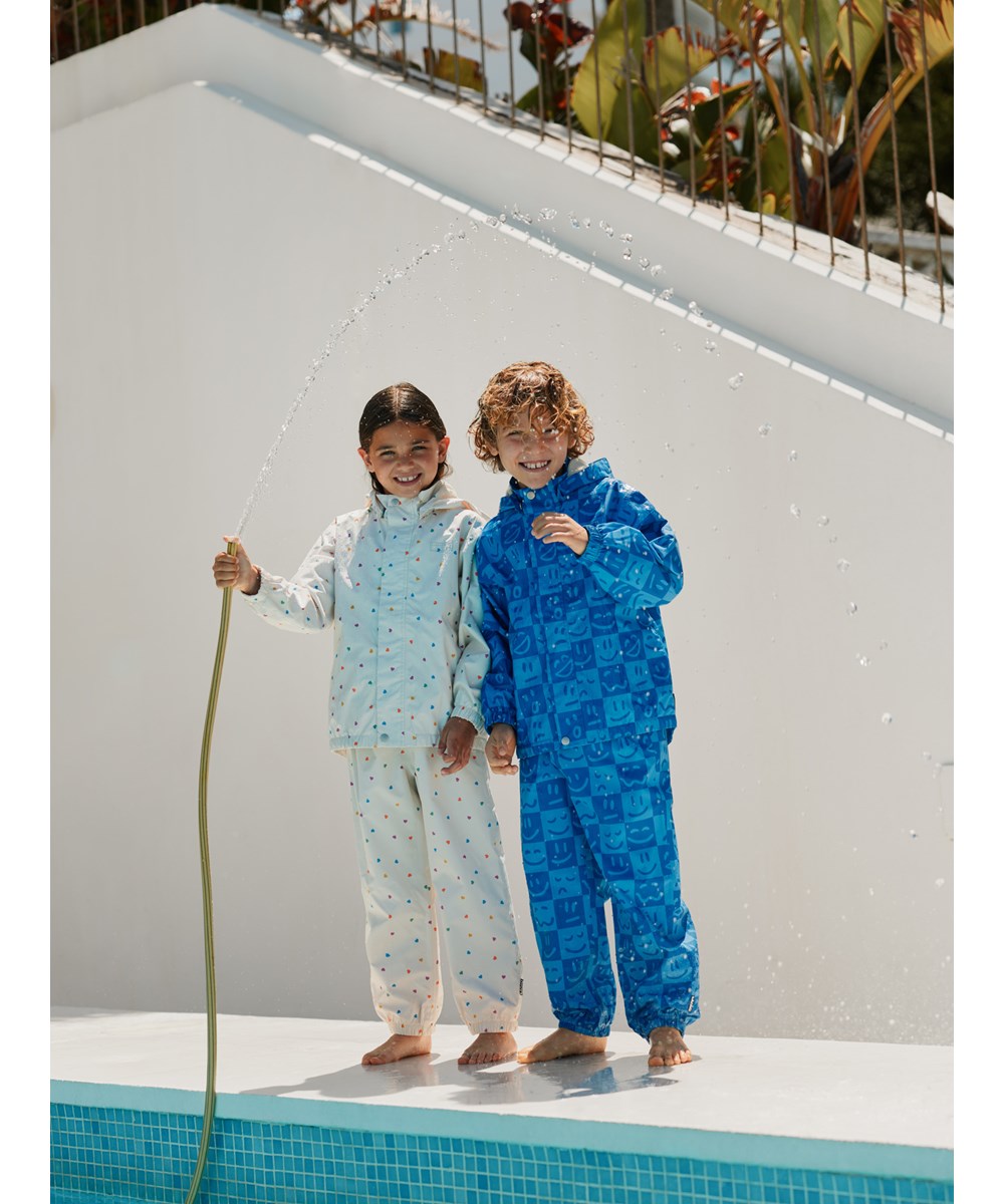 Waiton - Vibe Checks BLU - Wind and waterproof raincoat made from recycled polyester. The coat is in shades of blue with a checkered print of various emojis.