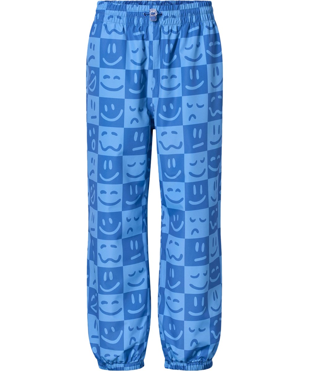 Waits - Vibe Checks BLU - Waterproof rain trousers in recycled polyester. The trousers are in shades of blue with a checkered print of various emojis.