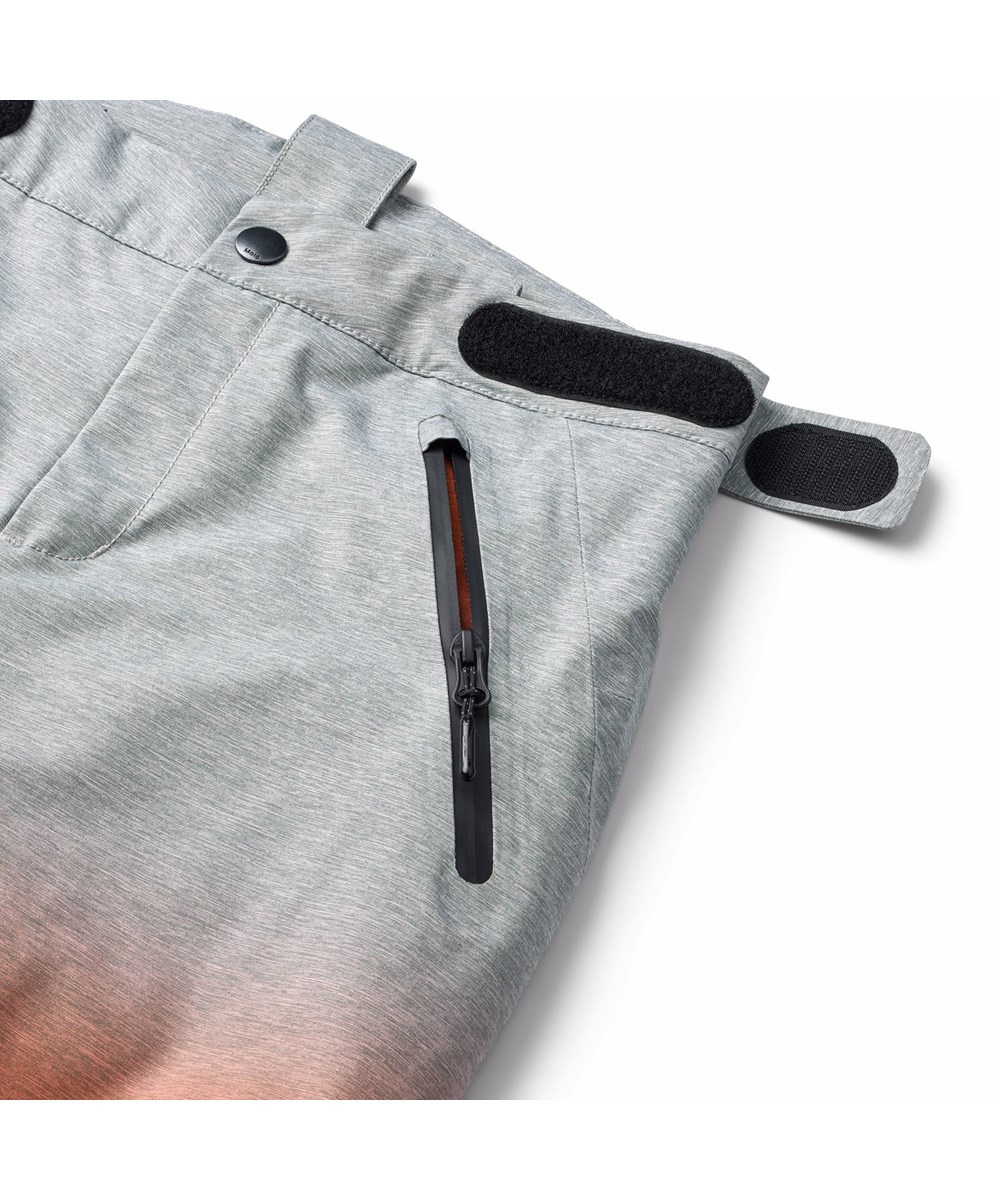 Jump Pro - Sunrise - Vind- og vandtætte overtræksbukser til børn i genanvendt polyester. Bukserne er grå, orange og blå med et print af snowboarder i alperne og vatteret med 3M™ Thinsulate™.