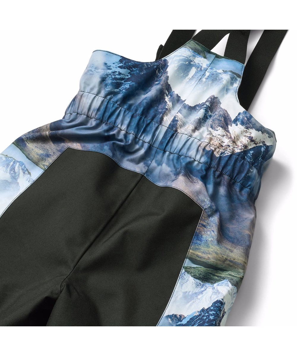 Play Pro - Snowy Mountains - Vind- og vandtætte overtræksbukser i genanvendt polyester, med et flot landskabsprint, der viser snedækkede bjergtoppe i klare farver. Bukserne har justerbare seler og er vatteret med 3M™ Thinsulate™.