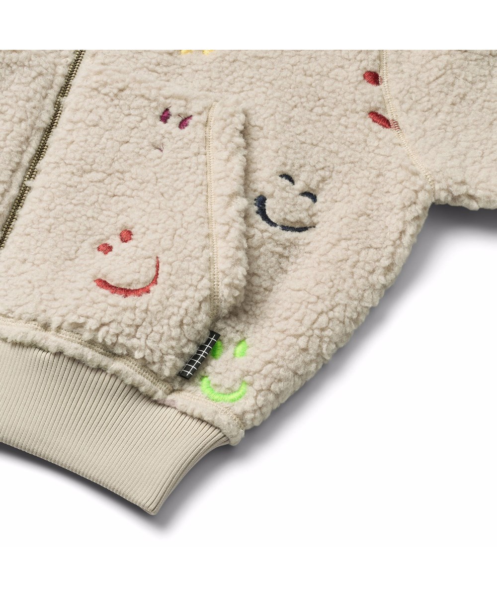 Hazzy - Teddy Emotions - Beige fleecejakke til børn i genanvendt polyester med broderet farverige smilende ansigter.