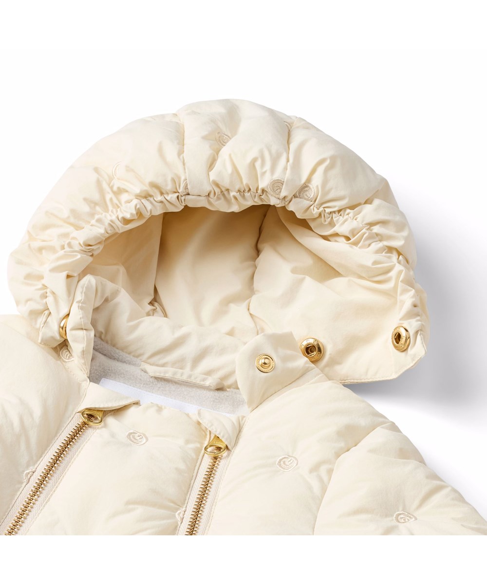 Hebe - White Noise - Vandafvisende blå babydragt med små broderet smilende ansigter fremstillet i genanvendt nylon.