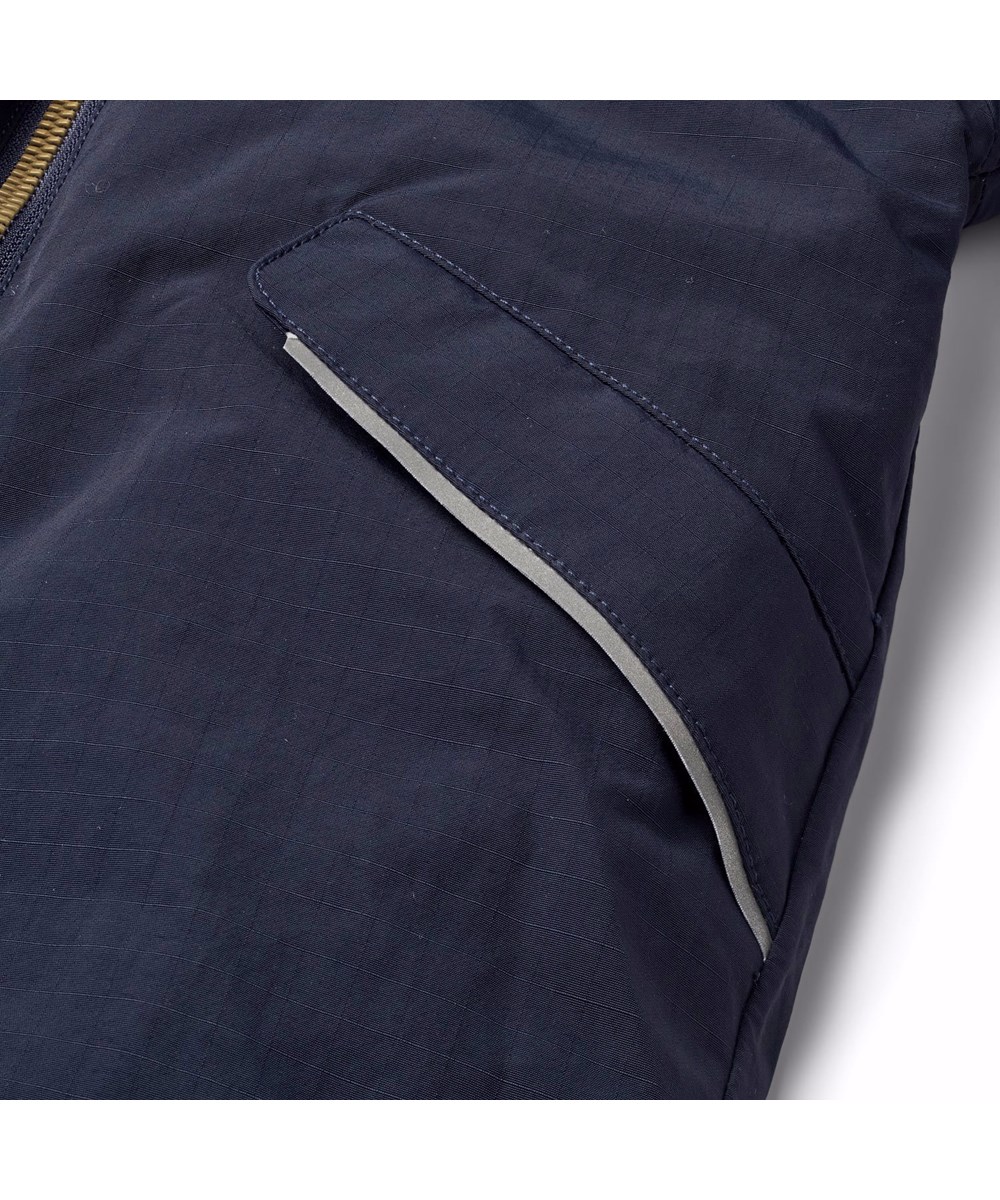 Hyde - Dark Night - Mørkeblå flyverdragt til en kold vinter i genanvendt polyester. Flyverdragten har elastik i lænden, ved ærme- og ben afslutning, så sne, regn og vind holdes ude, samt holder på luffer og støvler