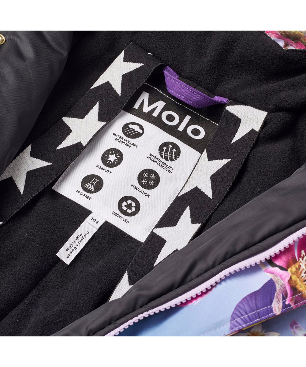 Polaris Fur - Gradient Bloom - Flyverdragt til en kold vinter i genanvendt polyester,  med et print af smukke blomster i friske farver på en blå og lilla baggrund. Dragten er vind og vandtæt og foret med 3M™ Thinsulate™