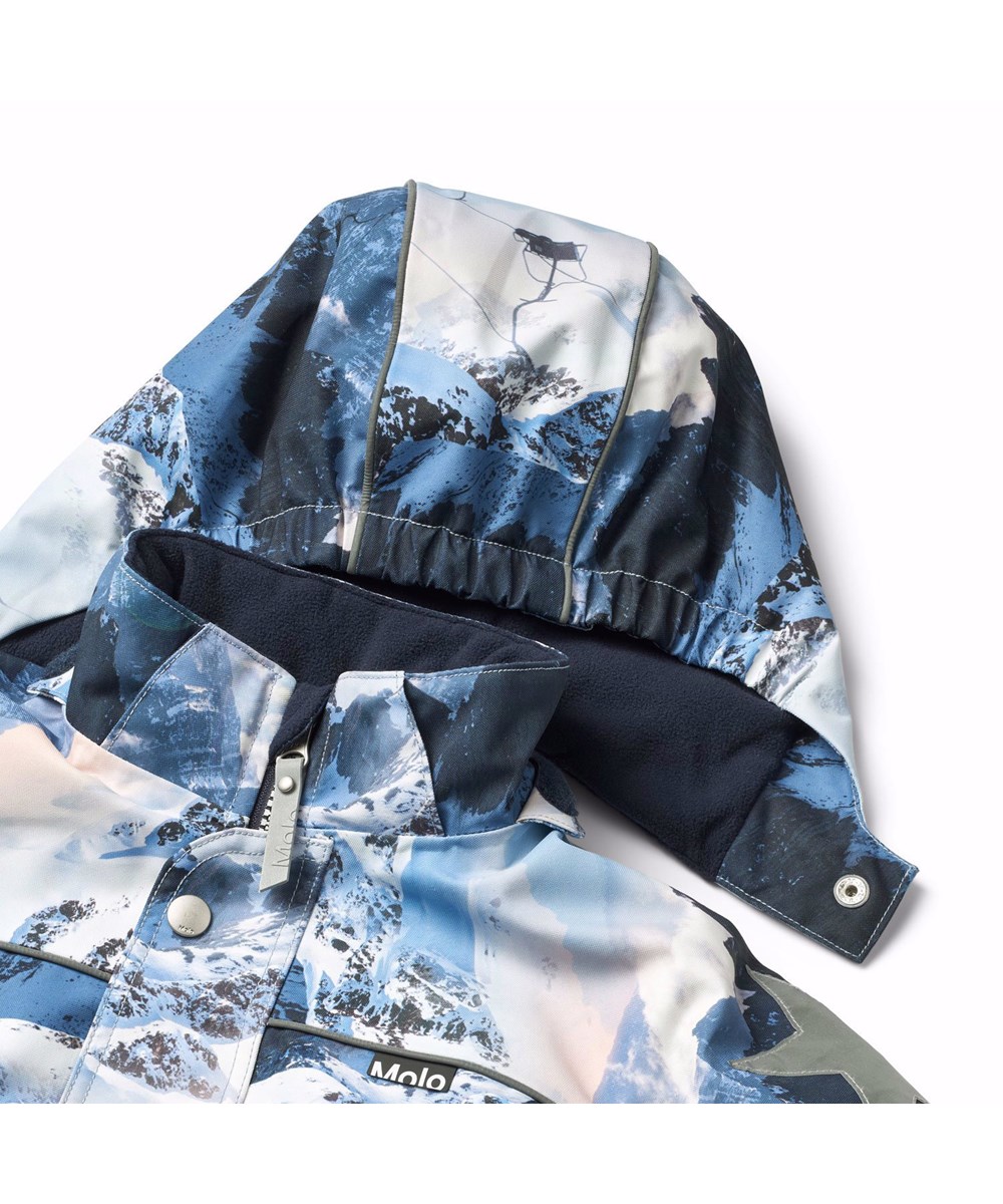 Polaris - Mountain High - Flyverdragt til en kold vinter i genanvendt polyester, med et print af snedækket alper i smukke blå nuancer. Dragten er vind og vandtæt og foret med 3M™ Thinsulate™