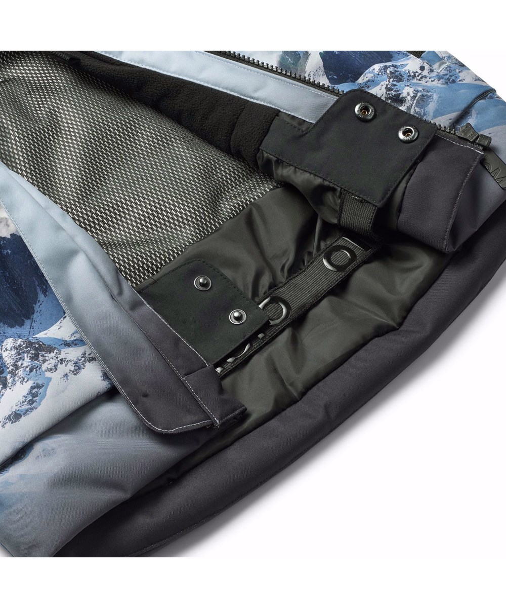 Alpine - High In Sky - Den perfekte vind- og vandtætte skijakke i genanvendt polyester, foret med fleece og 3M™ Thinsulate™, i et print af snedækket alper, solens skær og en klar på himmel