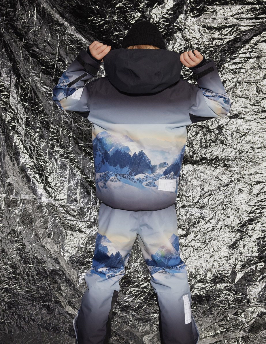 Alpine - High In Sky - Den perfekte vind- og vandtætte skijakke i genanvendt polyester, foret med fleece og 3M™ Thinsulate™, i et print af snedækket alper, solens skær og en klar på himmel