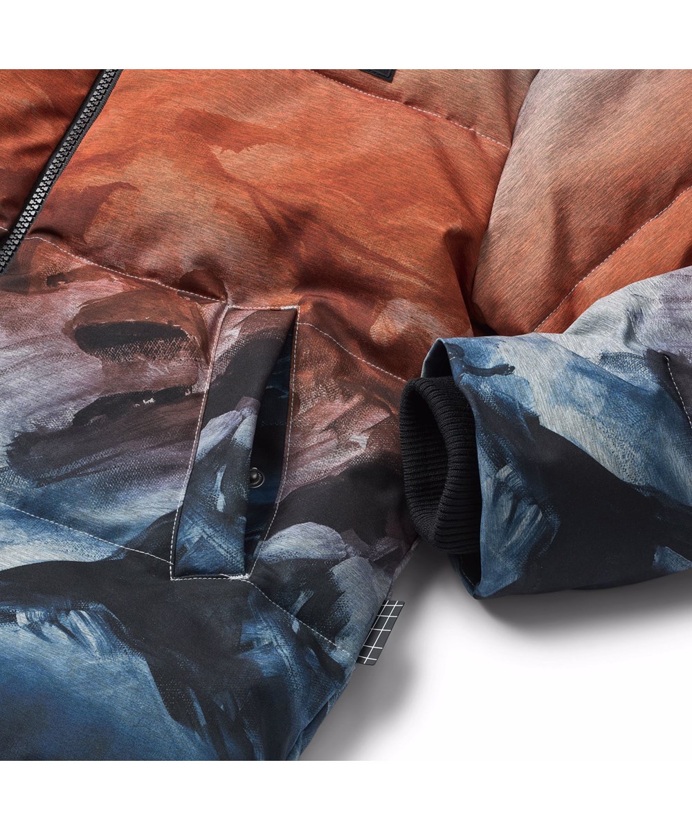 Hilo - Sunrise - Grå, orange og blå jakke til børn i genanvendt polyester med praktisk lynlåslukning, høj krave og aftagelig hætte.