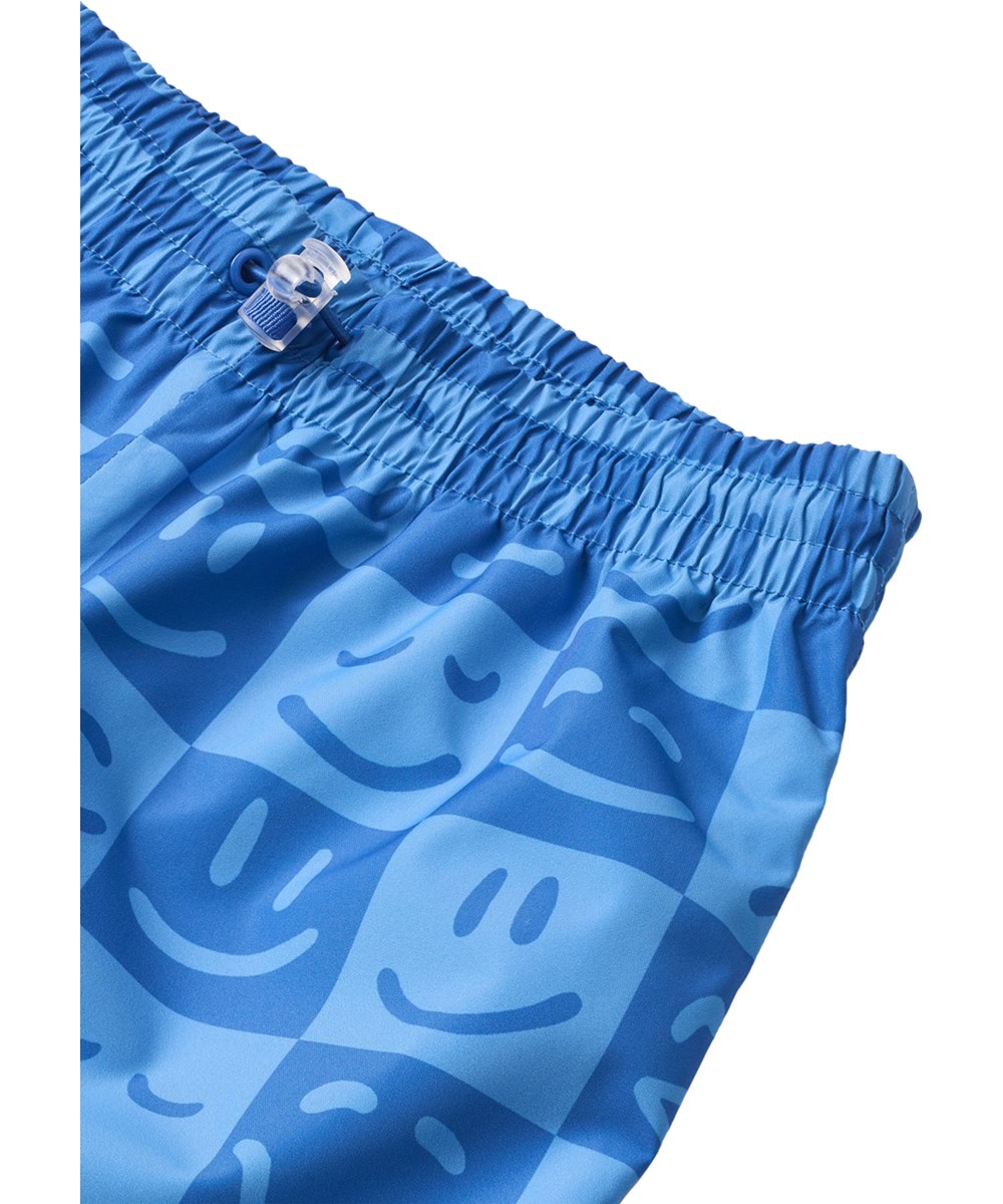 Waits - Vibe Checks BLU - Vandtætte regnbukser i genanvendt polyester. Bukserne er i blå nuancer med et ternet print af forskellige emojis