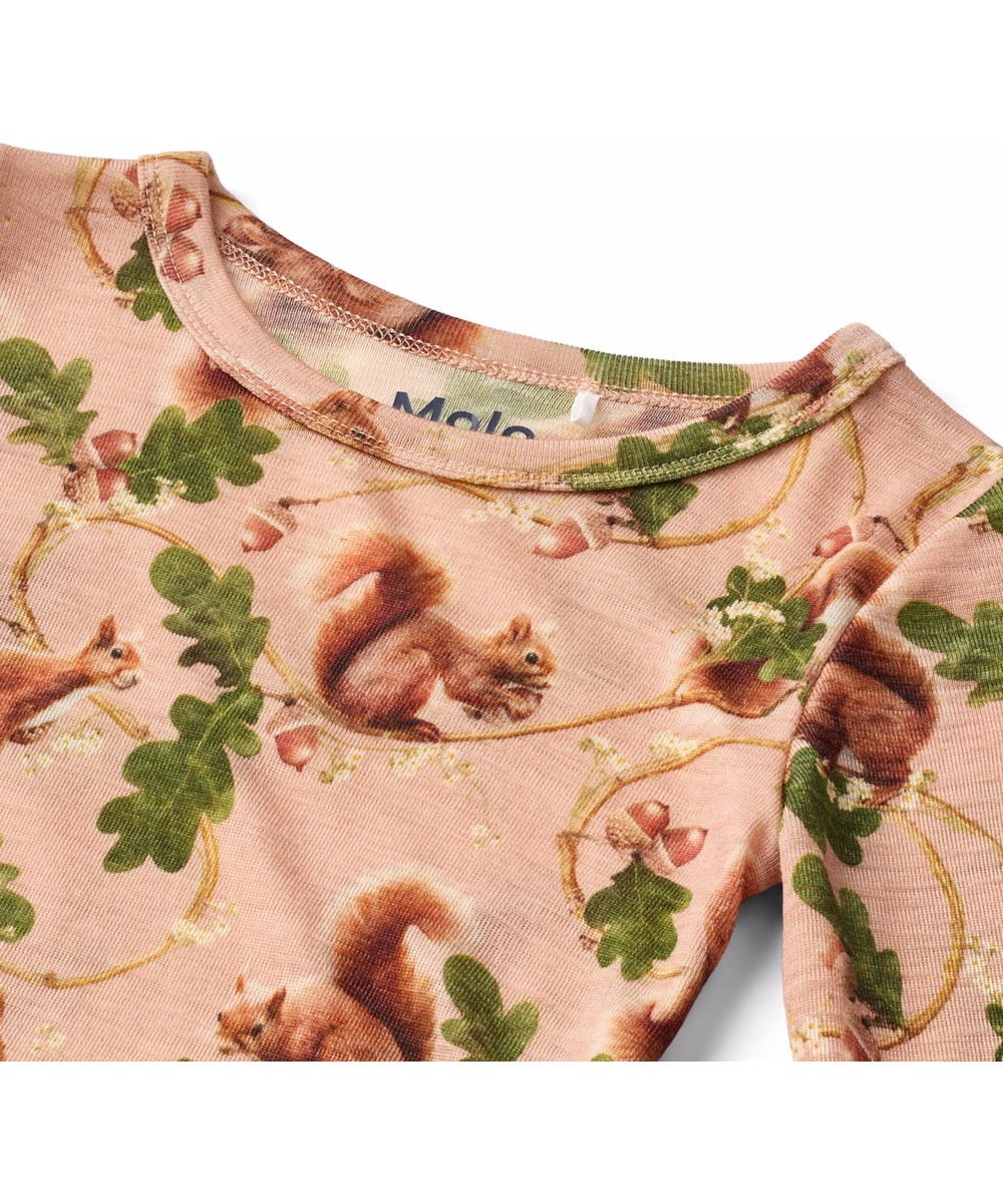 Rihanna Wool - Squirrel Harmony - Lyserød, langærmet bluse til børn i blød merinould med tætsiddende pasform, rund halsudskæring og babylock-detaljer ved ærmerne og nederste kant. Blusen har et print med egern på grønne egetrægrene.