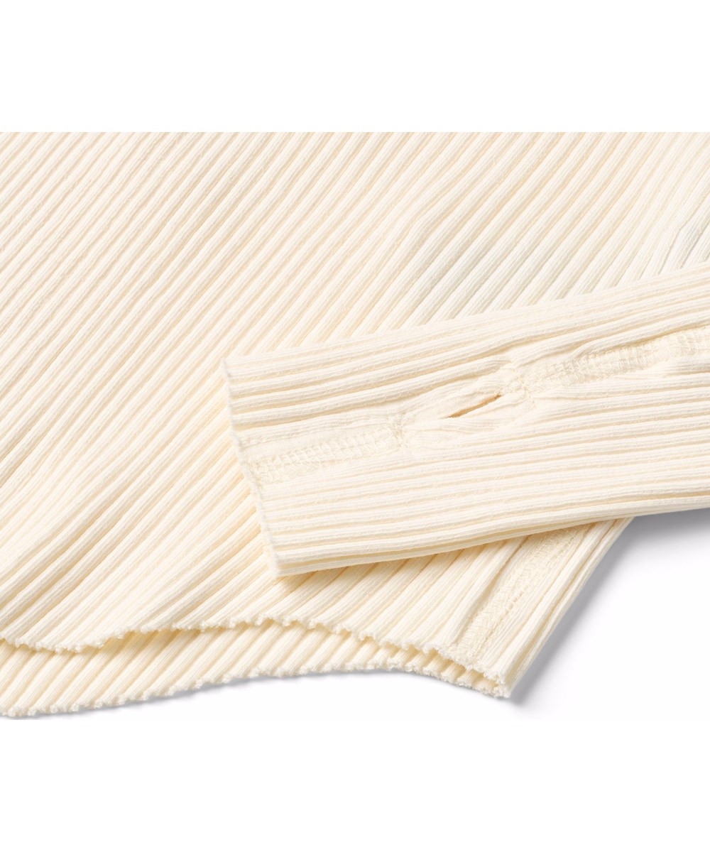 Rochelle - Buttercream - Råhvid langærmet bluse til børn i strækbart økologisk bomuldsrib med en tætsiddende pasform, rund halsudskæring, rå kanter ved begge ærmer med tommelfingerhuller.