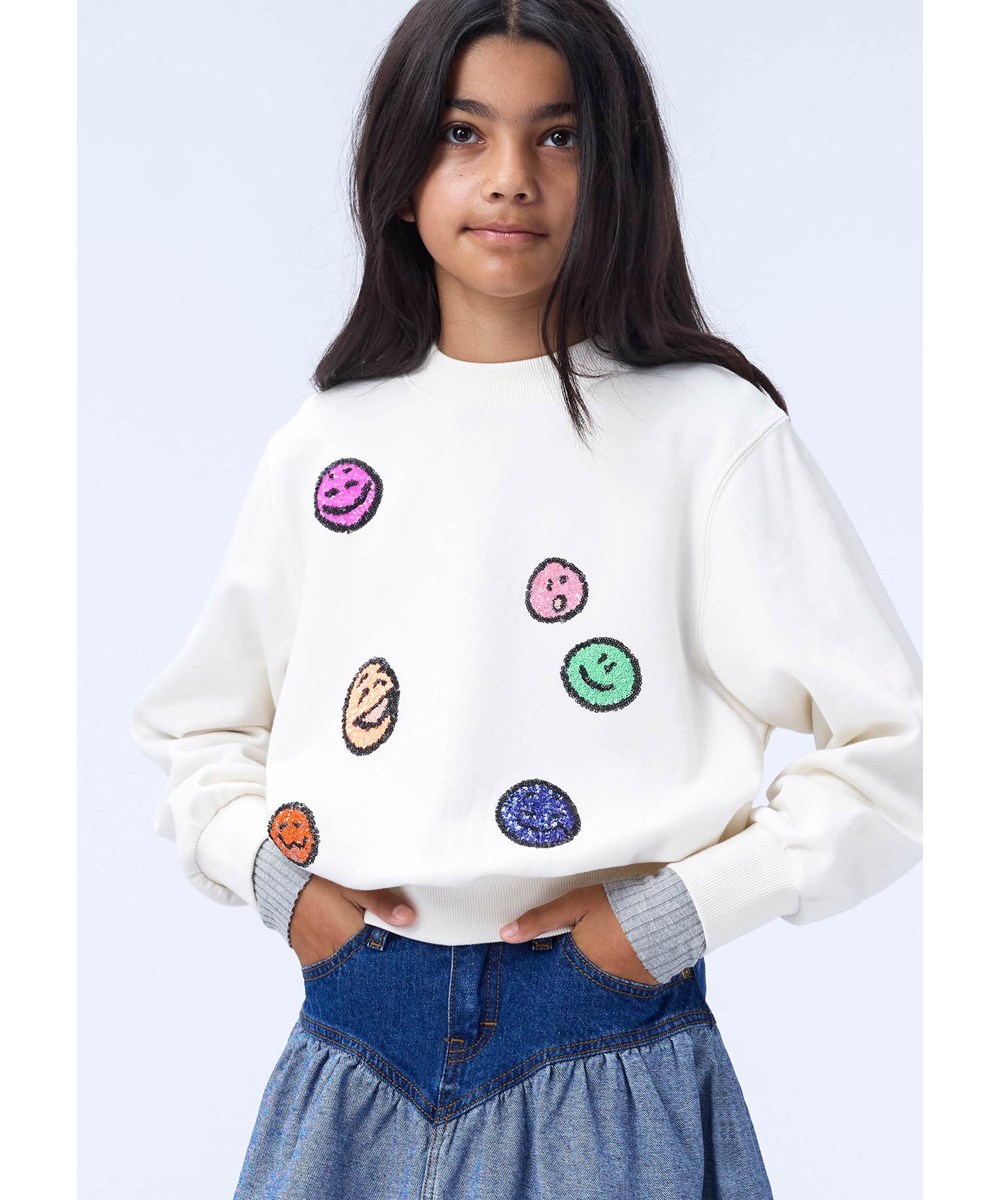 Marge - Buttercream - Råhvid sweatshirt til børn i økologisk bomuld med broderede paillet-ansigter.