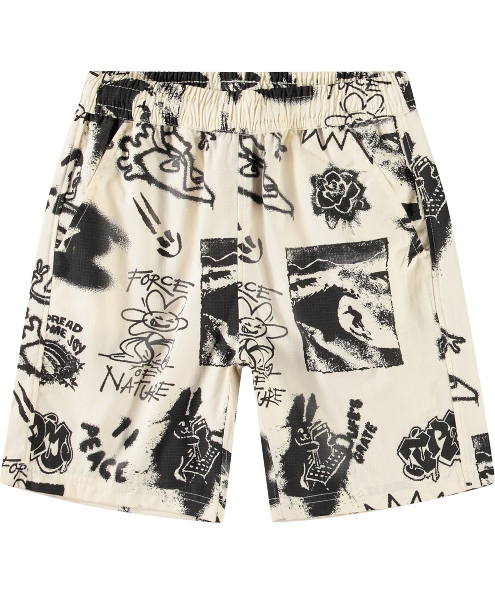 Avart - Art Mix - Knälånga shorts i ekologisk bomull för barn. Dessa shorts är beige skate-inspirerat mönster och coola uttalanden.