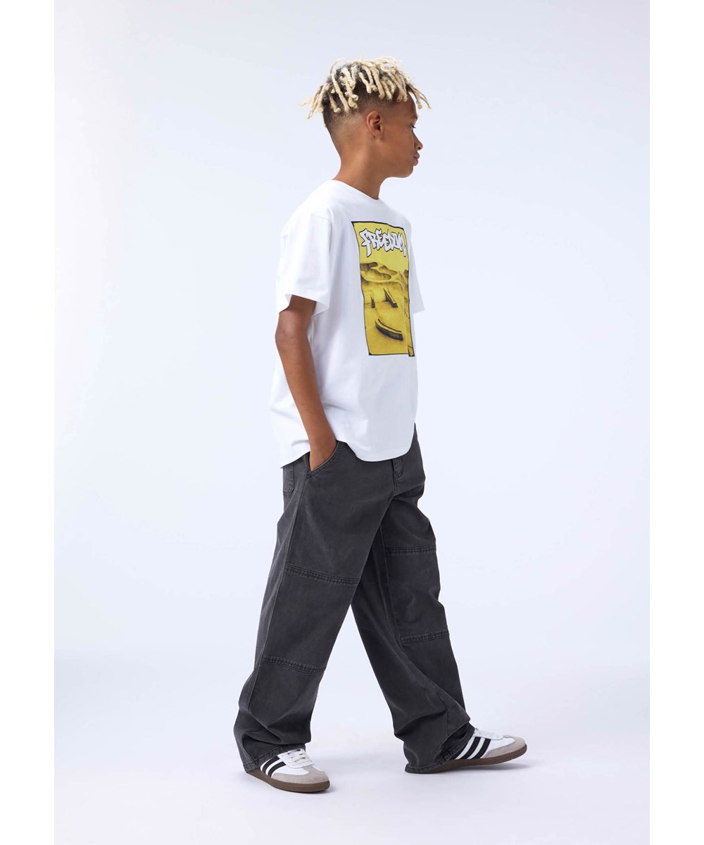 Riley - Yellow Skate - Vit T-shirt för barn i mjuk ekologisk bomull med tryck, korta ärmar och en ribbad halsringning.