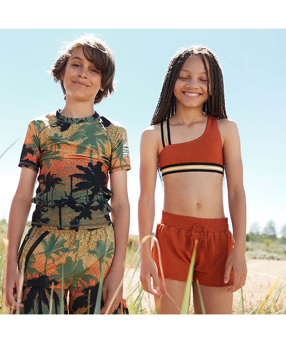 Nicci - Rusty - UV swim trunks in rust red with gold thread 