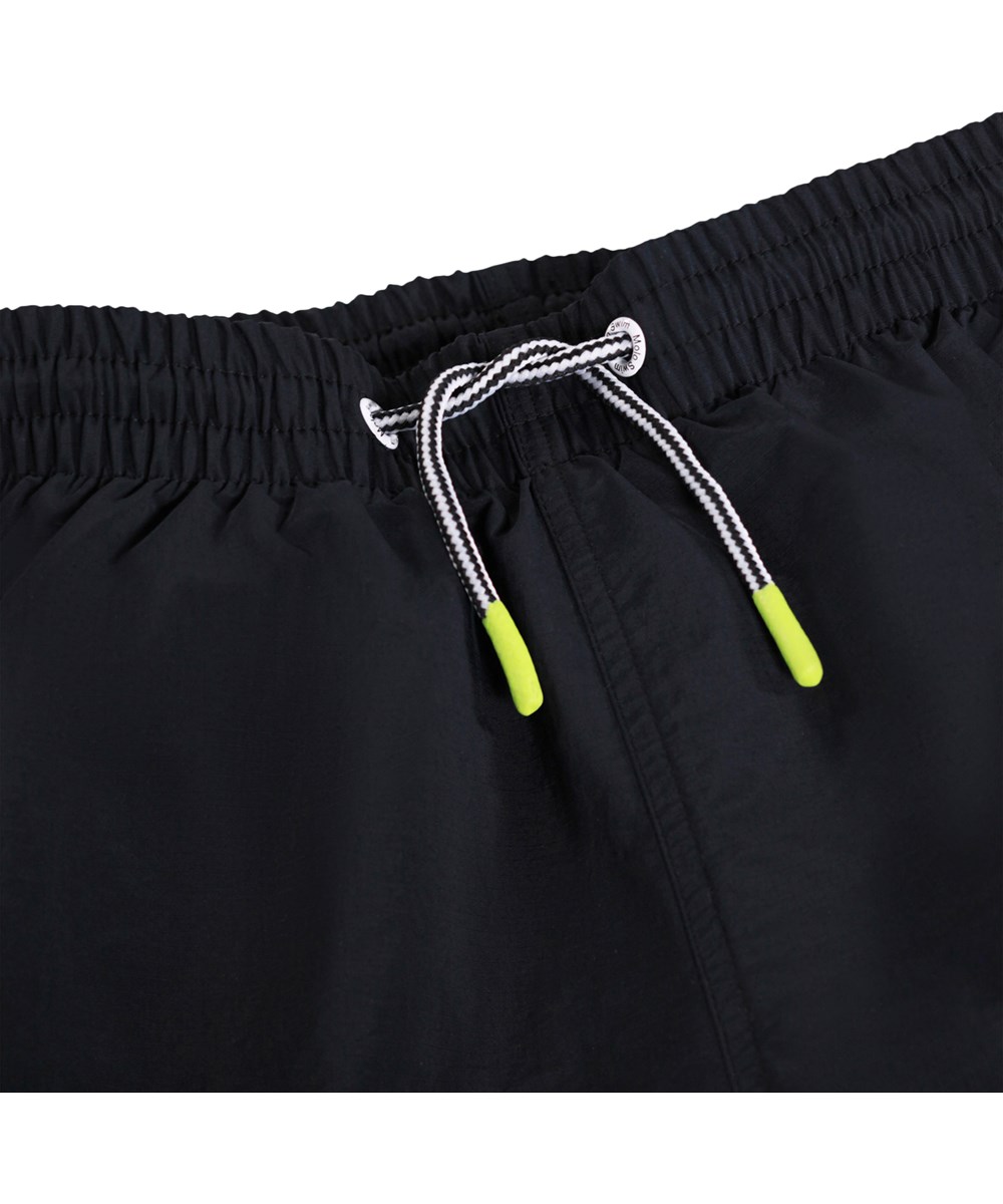 Niko Solid - Black - Black, sporty swim shorts for children made of recycled nylon with UV protection 50+.