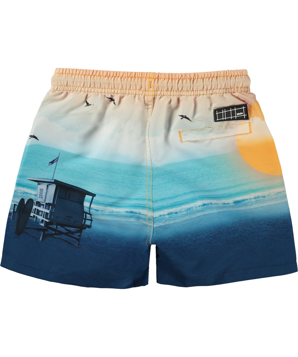 Niko - Sunset Beach - Blue and orange swim shorts with short legs and placement beach print 