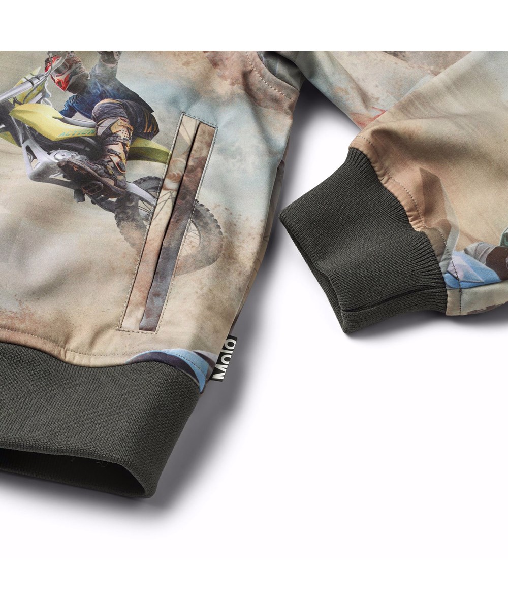 Cloudy - Dusty Cross - Vind- och vattenavvisande softshelljacka för barn i återvunnen polyester, med en motocrossförare i bruna toner.