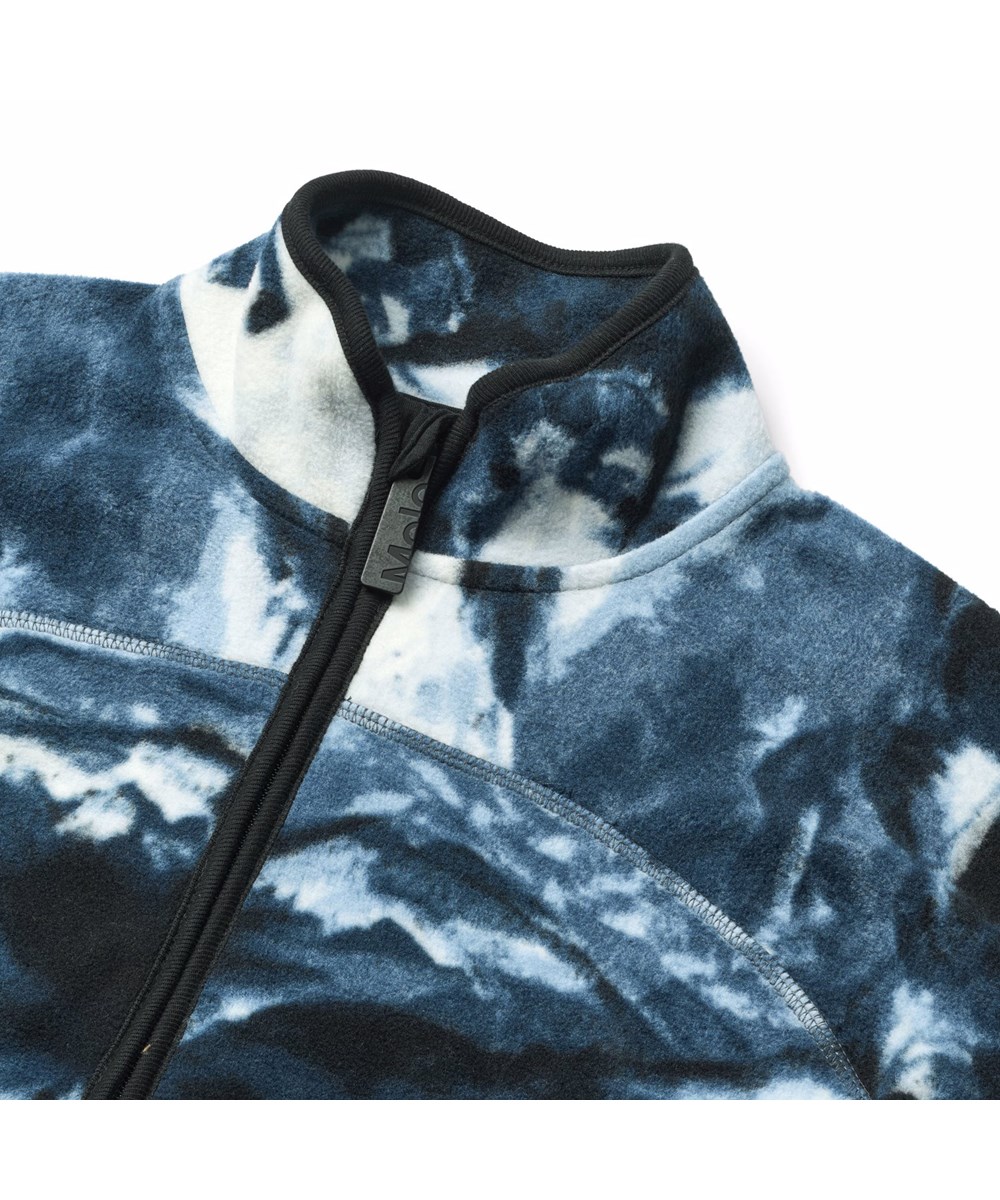 Ulani - Arty Mountains - Blå fleecejacka för barn tillverkad av återvunnen polyester med mörkblå ribbade kanter och en framficka.