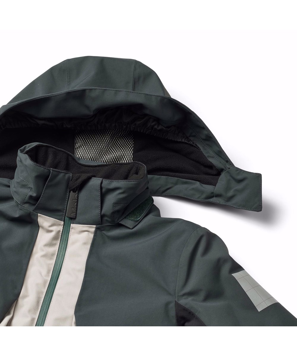 Alpine - Block - Petroleumgrön och sandfärgad vind- och vattentät skidjacka för barn i återvunnen nylon och polyester.