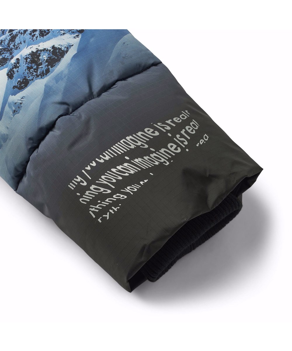 Hilo - High In Sky - Varm dunjacka för barn i återvunnen polyester med ett tryck av snöklädda alper med solstrålar och en klarblå himmel.