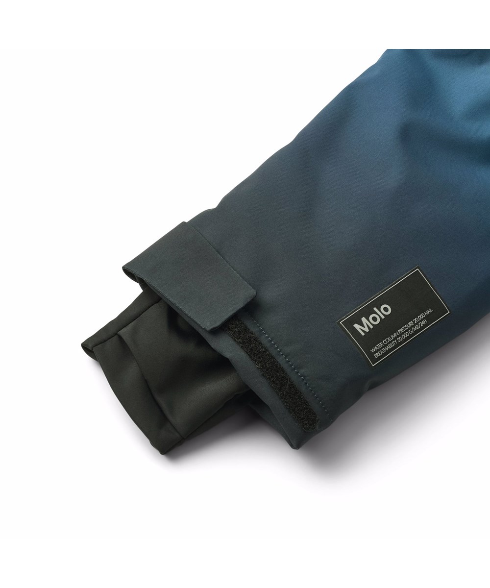 Hux - Blue Ice - Vind- och vattentät overall i blå gradientfärger för en kall vinter eller skidsemester i återvunnen polyester och vadderad med 3M™ Thinsulate™.