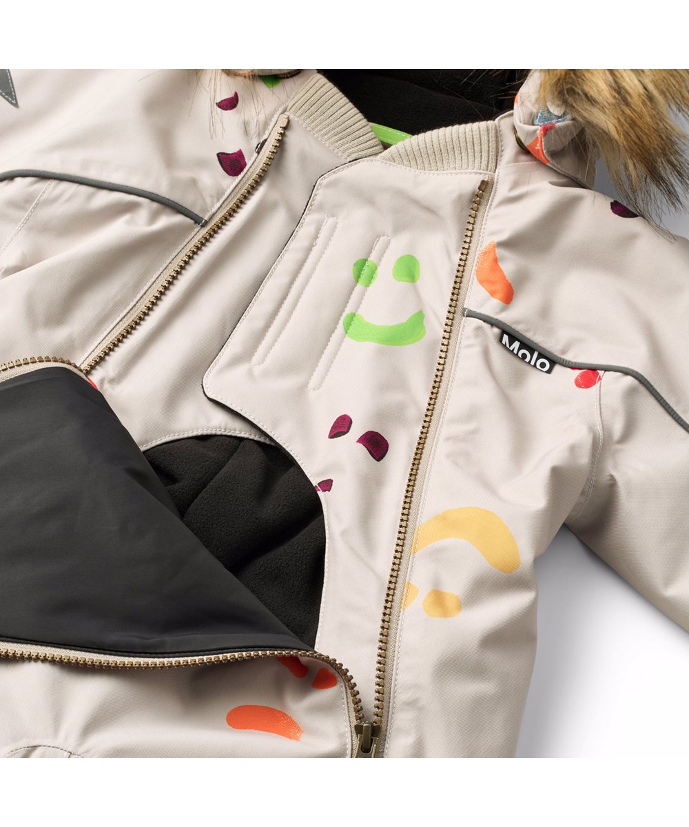 Pyxis Fur - Arty Emotions - Beige vind- och vattentät overall för en kall vinter med färgglada smileys tillverkad av återvunnen polyester och vadderad med 3M™ Thinsulate™.