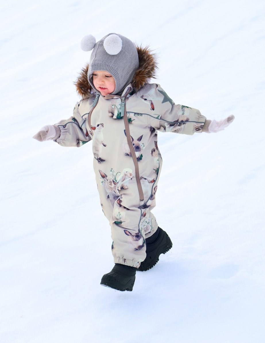 Pyxis Fur - Winter Rabbits - Barnoverall i återvunnen polyester med ett tryck av söta kaniner bland snödroppar på en grå bakgrund.